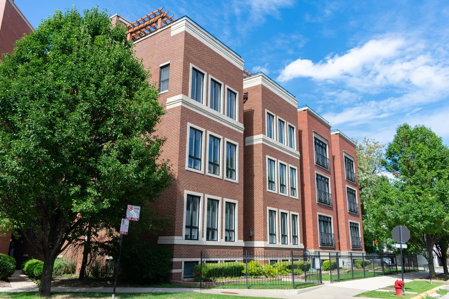 A brick multifamily building on a tree-lined street