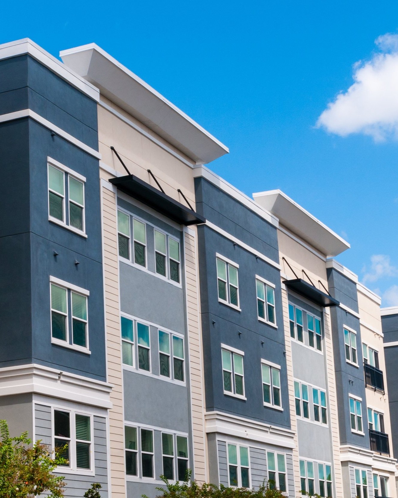 A four-story multifamily building against a blue sky